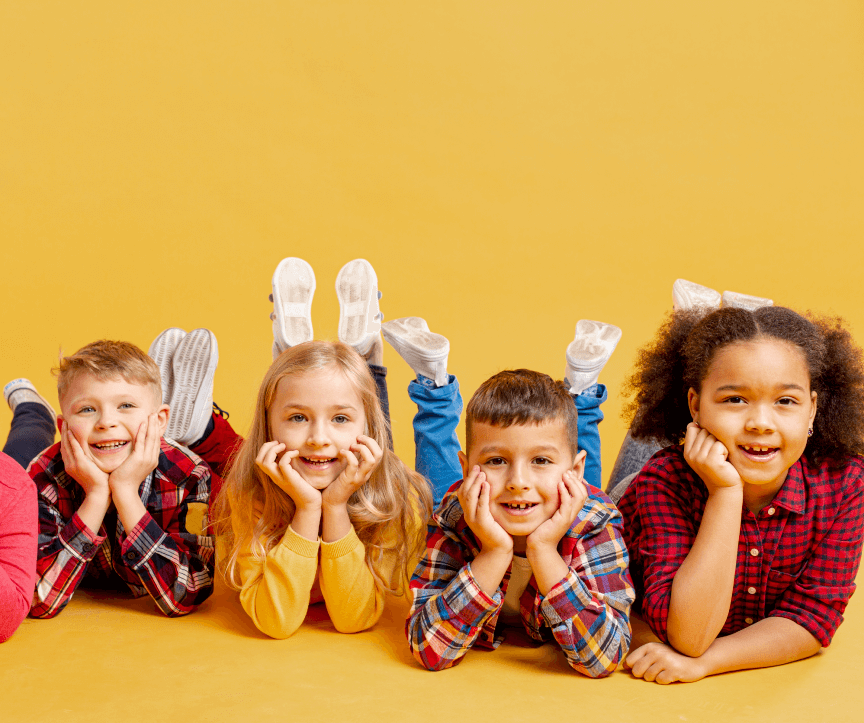 foto de 4 crianças de bruços, com as mãos no queixo e sorrindo