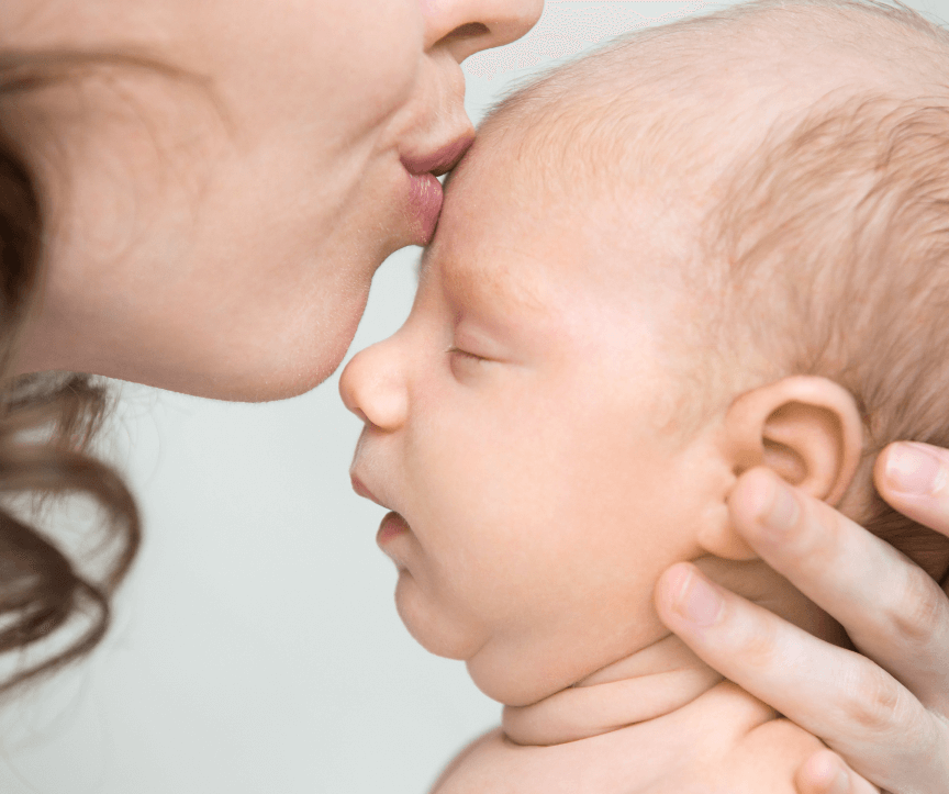 foto de uma mãe beijando a testa de um bebê