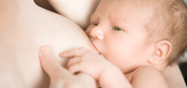 foto de um bebê recém-nascido mamando no seio materno